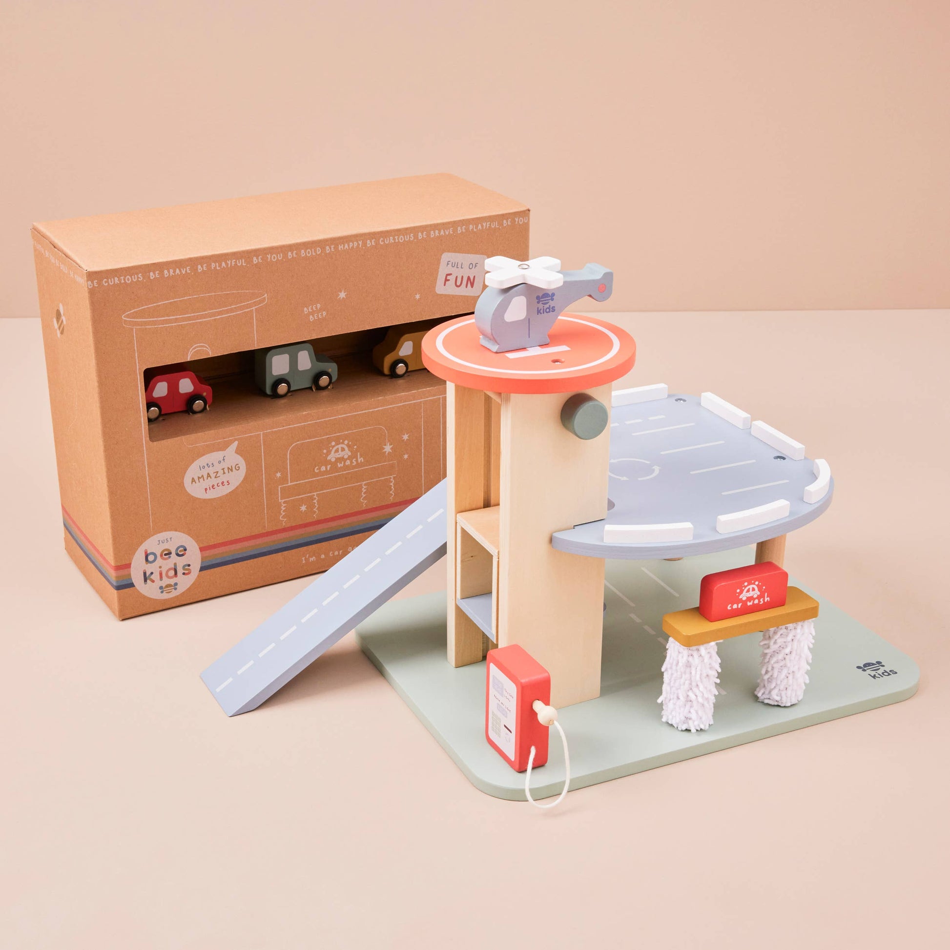 Toy set with a helicopter, cars, and a ramp in front of its packaging on a beige background