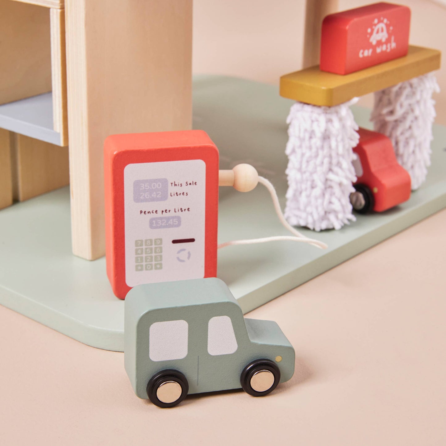 Wooden toy car and phone set on a pastel-colored surface